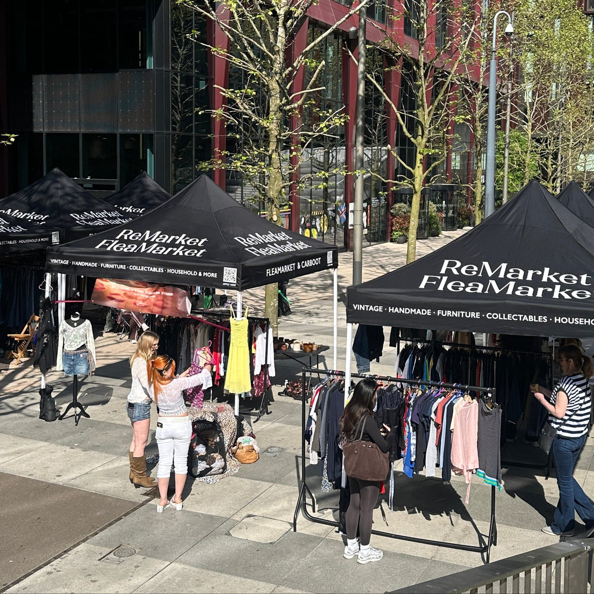 Flea market with 'ReMarket Flea Market' tents in an urban setting.